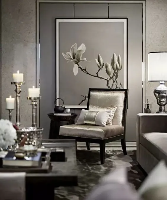 Grey-on-grey living room corner with a dark-framed champagne silk armchair set against an oversized framed magnolia painting