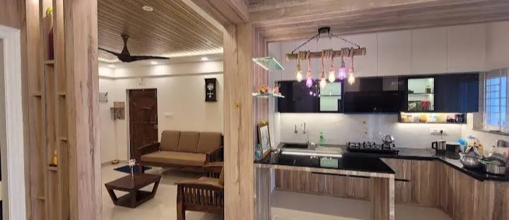 Wide open-plan frame from a wood-clad archway: a brown fabric sofa and low teak coffee table under a slatted wood ceiling on the left
