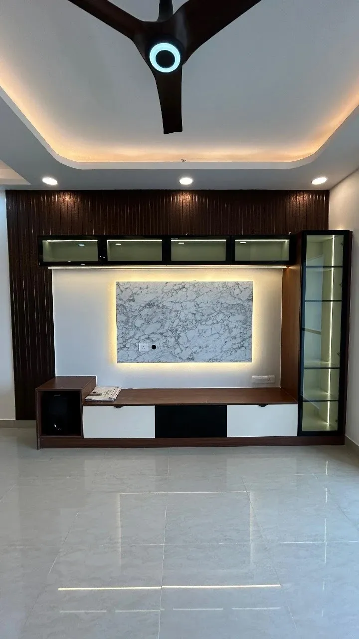 Dark fluted wood TV wall with a backlit marble-look centre panel, a row of four glass-front lofts