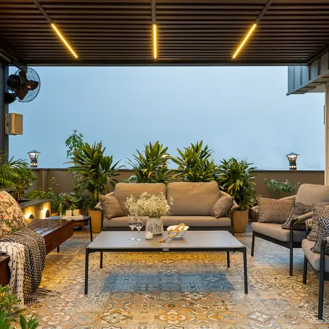 Covered rooftop terrace lounge with patterned cement-tile flooring, grey outdoor sofas, and a slatted pergola with linear