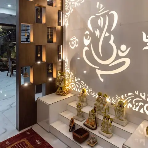 Pooja room with a backlit laser-cut Ganesh motif jaali wall, a stepped marble idol platform, and a wood partition with