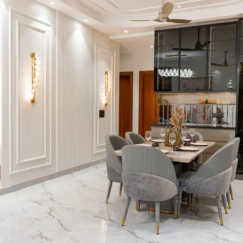 Open living-dining space with a pink-grey marble slab TV feature wall, gold bubble wall sconces, a marble dining table with