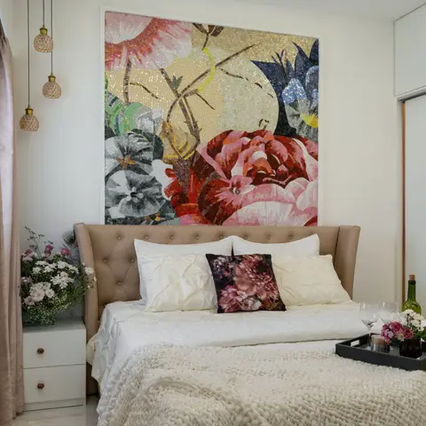Bedroom with a tufted taupe leather wingback headboard beneath a large floral mosaic wall art panel, glass pendant lights,