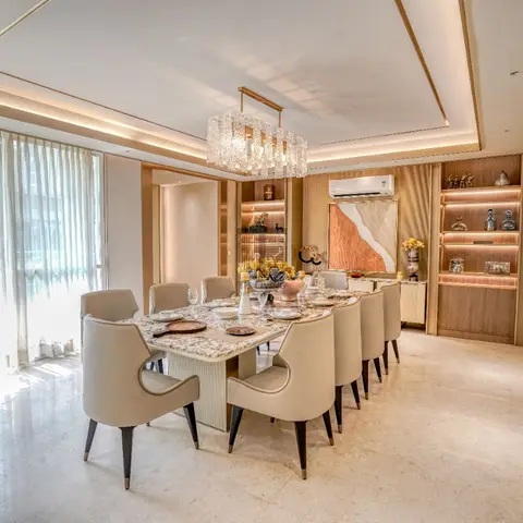 A formal dining room with a long marble-top table seating ten in taupe leather chairs, a linear crystal chandelier, and