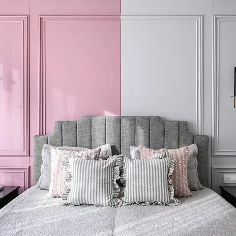 symmetrical bedroom with a split pink-and-grey moulded panel headboard wall and matching marble-capsule pendant lights on