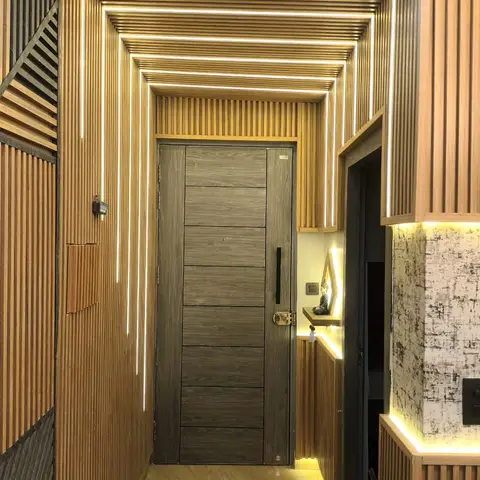 entrance foyer with a concentric fluted-wood arch framed by embedded LED light strips leading to the main door