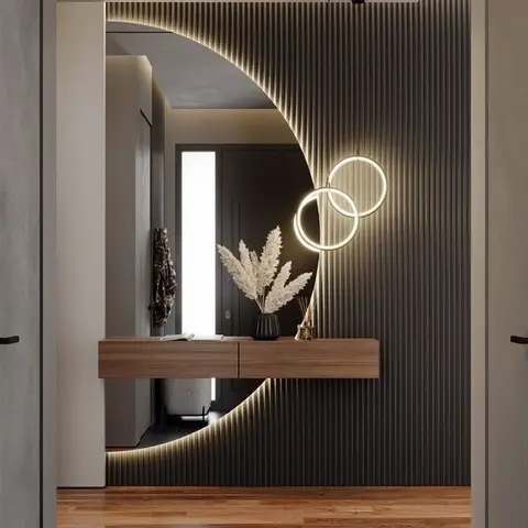 entrance foyer with a backlit fluted wall panel cut into a crescent moon around a mirror, twin illuminated ring lights, and