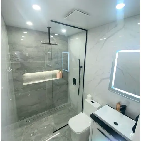 a luxury bathroom with a frameless glass walk-in shower, black ceiling-mounted rain shower head, grey-veined marble tile, a
