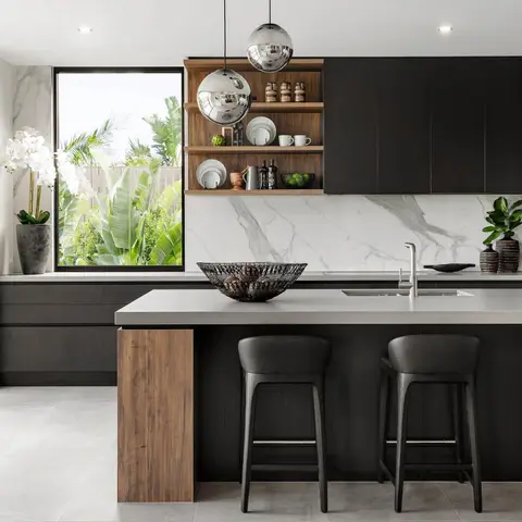 Kitchen island in matte black handleless cabinetry with a wood-clad end panel, a book-matched marble slab backsplash, twin