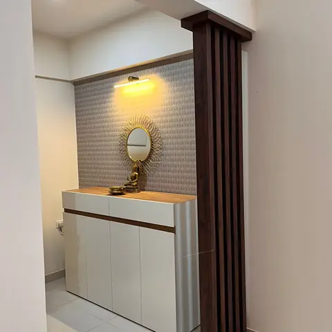 Entrance foyer with a fluted dark-wood partition column beside a glossy white shoe cabinet topped with a sunburst mirror and