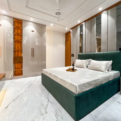 Primary bedroom with an emerald velvet bed against a mirrored fluted feature wall, a full-height glossy wardrobe with a wood
