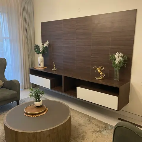 Living room floating TV console in dark wood-look tile cladding with brass horse and figure sculptures, flanked by