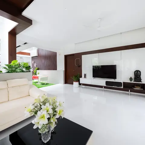 Open living room with a glossy white floor, cream leather sofa facing a dark wood-veneer TV feature wall, and an indoor