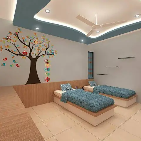 A kids' bedroom with twin built-in platform beds in blue bedding, beneath a curved two-tone pop ceiling, and an owl-and-tree