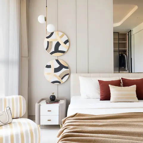 Upholstered-panel bedroom wall with two round gold-and-black wall discs beside a bed, with an open walk-in wardrobe visible