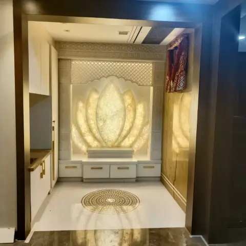 A pooja room with a backlit carved-onyx lotus-petal feature wall framed by a jaali lattice screen and swastika border, a