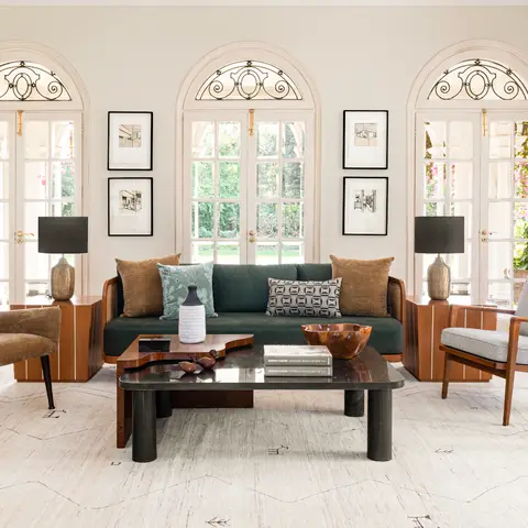 Colonial-arched living room with a dark green velvet sofa, black stone coffee table and mid-century armchairs on a patterned