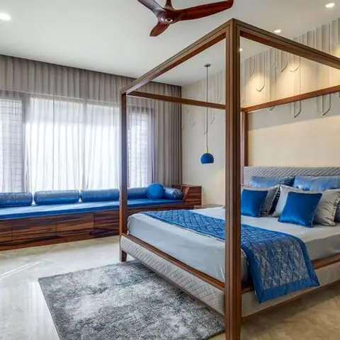 Bedroom with a dark wood four-poster canopy bed dressed in blue and grey quilted bedding, a matching built-in blue window