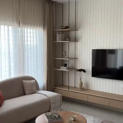 Living room with a beige sofa and rust-colored accent sofa around a fluted round coffee table, a hanging ladder-style