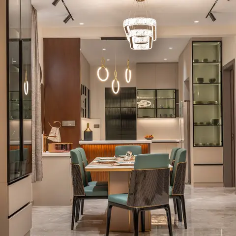 A marble-top dining table with teal leather and black fluted chairs sits beneath a tiered crystal chandelier and trio of