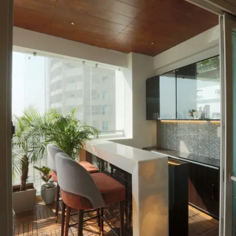 A home balcony converted into a bar nook with wood deck tiles, a wood-clad ceiling, a marble-topped bar counter with glossy