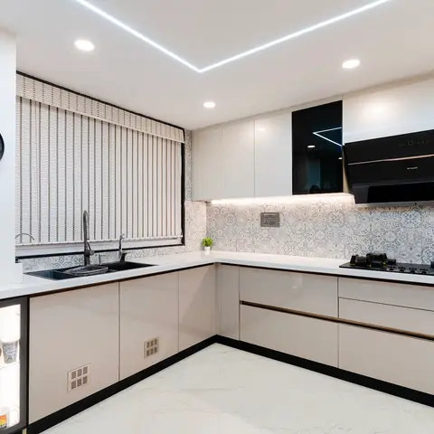 L-shaped modular kitchen with high-gloss cream shutters, a patterned Moroccan-tile backsplash, and a black chimney hood