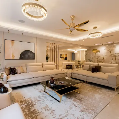 Living room with a beige L-shaped leather sectional, dual crystal ring chandeliers, a gold ceiling fan, and a gold