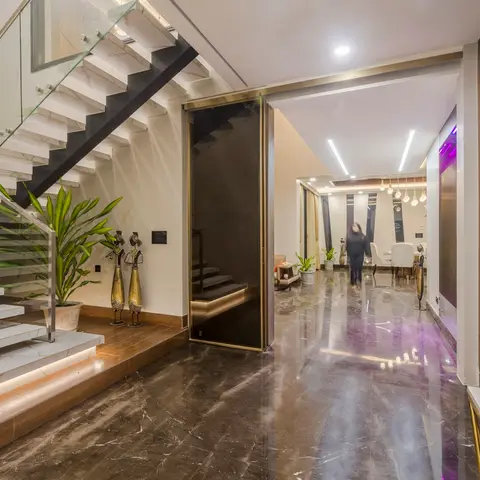 Villa entrance foyer with a floating white marble staircase behind a glass balustrade, dark marble flooring and a