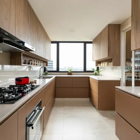 U-shaped high-rise kitchen with warm walnut and taupe matte cabinetry, white quartz countertops, an integrated island, and a