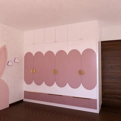 Kids' bedroom wardrobe wall with scalloped dusty-pink cloud-shaped door fronts and brass half-moon handles, beside a