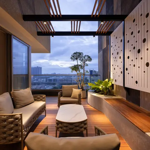 Balcony lounge with woven outdoor sofa seating around a marble-top coffee table, a wood deck floor, potted plants, and a