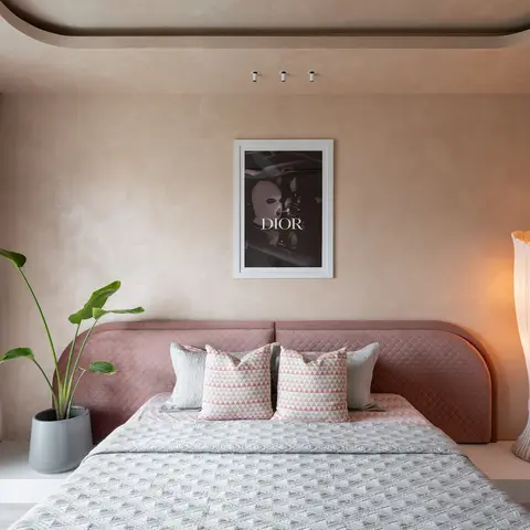 Bedroom with hand-textured plaster walls, a dusty-rose upholstered bed, and a sculptural ribbed floor lamp beside a framed