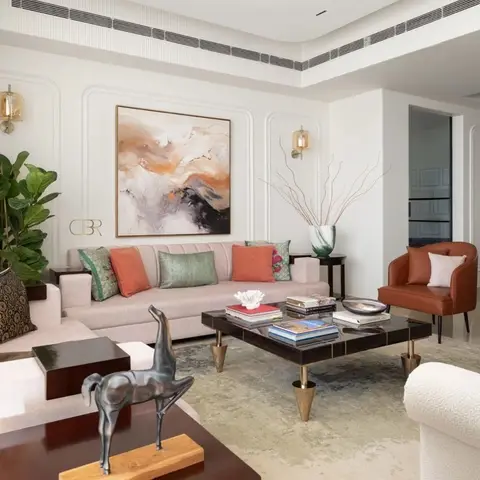 Living room with arched wall panel moulding behind a blush sofa styled with terracotta and sage cushions, a large abstract