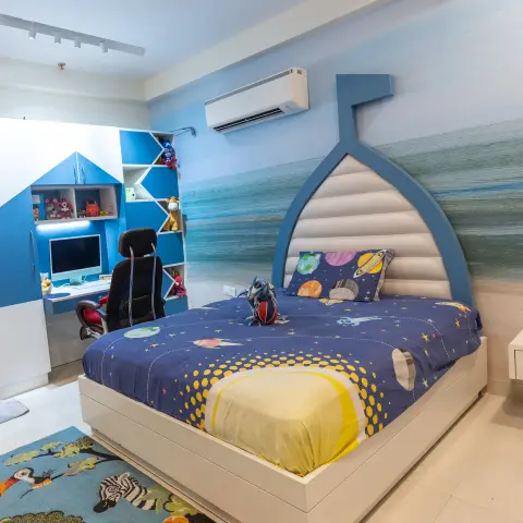 Kids' bedroom with a custom boat-shaped bed against an ocean-mural wall, a built-in blue study unit, and an animal-print