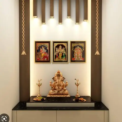 Pooja unit with a fluted wood surround, brass hanging bells, a gold Ganesh idol, and a black granite platform over closed