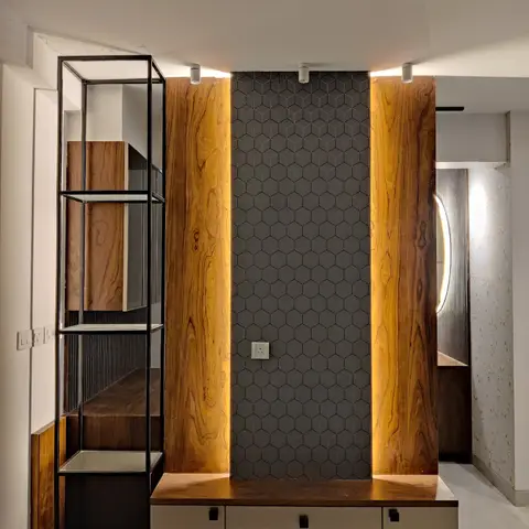 TV feature wall with book-matched wood-veneer pillars flanking a charcoal hexagon-tiled backsplash, beside an open