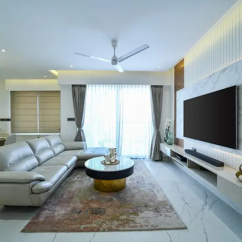 Living room with a grey leather sectional sofa facing a round marble-and-brass coffee table, set before a backlit