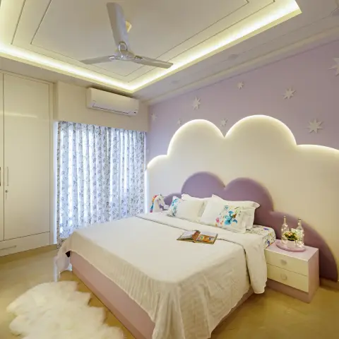 Kids' bedroom with a backlit cloud-shaped upholstered headboard against a star-painted lavender wall, a sheepskin rug, and a