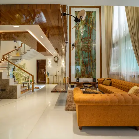 Double-height living room with a backlit green onyx wall panel, a mustard leather chesterfield sofa, and a wood-clad