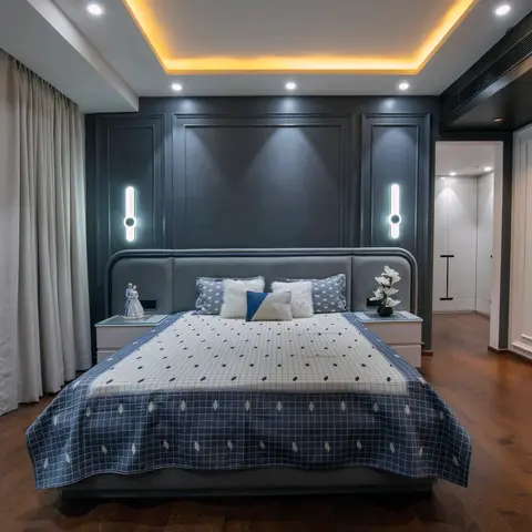 Grey king bedroom with a dark moulded panel headboard wall, warm cove-lit stepped ceiling, sheer patterned curtains and a