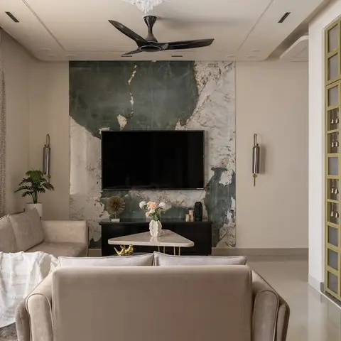 Living room with a book-matched green marble TV feature wall, beige velvet sofas, a black fluted TV console, and a painted