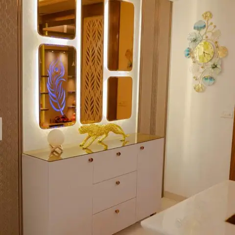 Entrance console vignette with a backlit asymmetric mirror-and-jaali panel cluster, a white console cabinet with brass