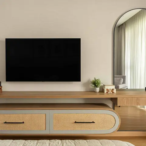 Bedroom with a floating wood TV console featuring rattan cane-front drawers that extends into a dressing table with an