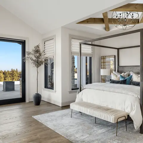 Vaulted-ceiling primary bedroom with an exposed wood truss beam, a black four-poster canopy bed dressed in teal accent