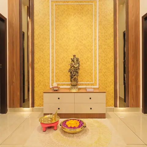 Foyer with a gold floral wallpaper feature wall framed by white moulding, a beige console table displaying a brass Krishna