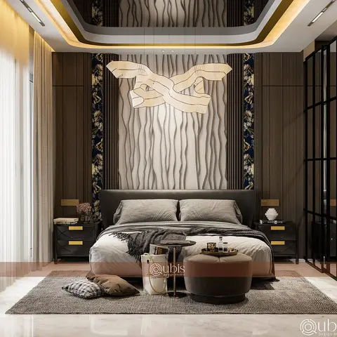 A dark upholstered king bed sits beneath a sculptural ribbon pendant light against a wavy wood-panel and floral-wallpaper