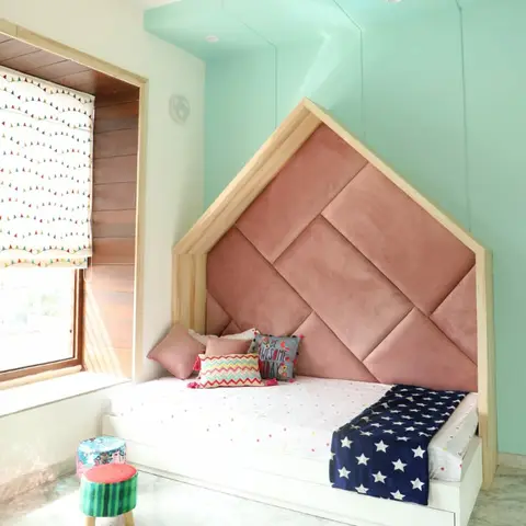 Kids' bedroom with a house-shaped upholstered blush headboard nook against a glossy mint wall, styled with a starry navy