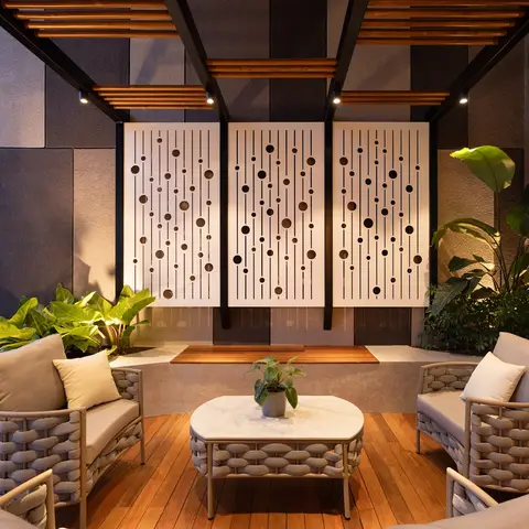 Terrace lounge with woven rope armchairs around a marble-top coffee table, a wood pergola overhead, and three perforated
