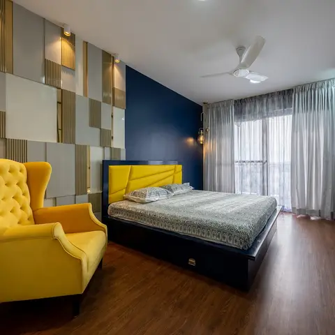 Bedroom with a mustard channel-tufted upholstered headboard and matching wingback chair against a navy accent wall, backed