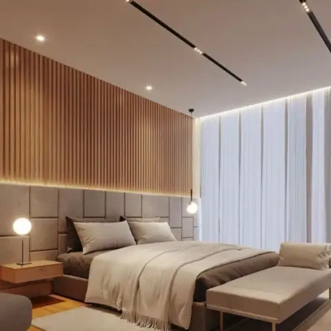 Master bedroom with a full-height fluted wood-slat accent wall above a grey channel-tufted upholstered headboard, sheer